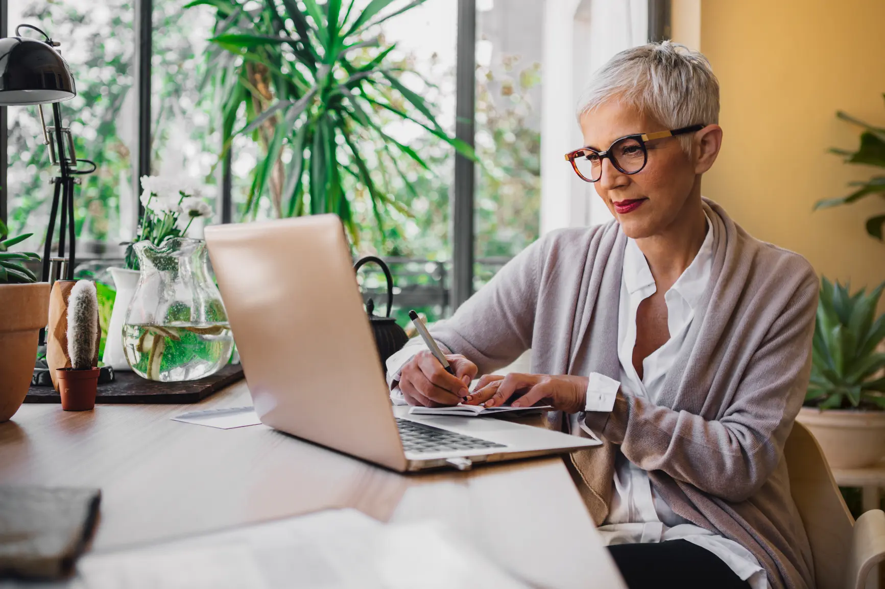 Woman sitting at her desk and writing in her notebook.