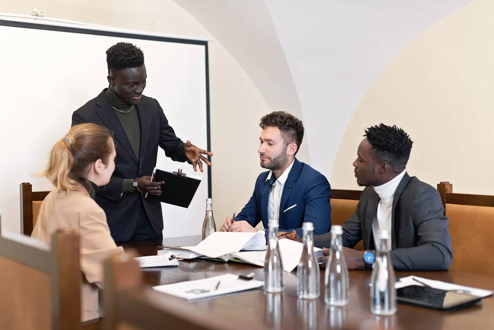Header image of 4 colleagues around a brown table, one standing while the others seated, giving a presentation | Understanding Unillateral Contract Modification